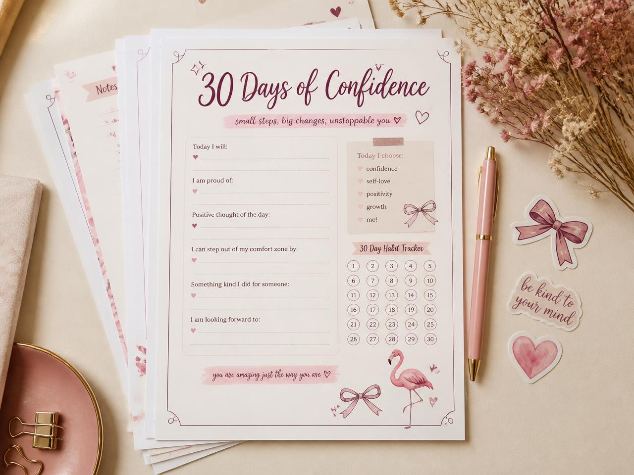 Printed pages of the 30-Day Confidence Journal with a habit tracker, stickers and a pink pen